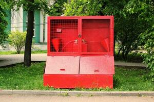 Red fire prevention shield stand with fire extinguishing tools in city park. Special fire buckets and a shovel. Set of firefighting equipment photo