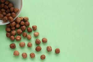 Hazelnut on white ceramic bowl on green background. Healthy eating diet, nutrition, vegan concept. Protein organic food. Dry snack. National nut day. Copy space for text photo