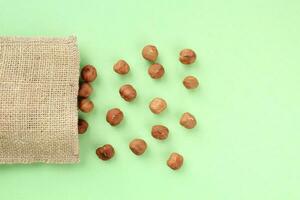 Hazelnut on eco canvas bag on green background. Healthy eating diet, nutrition, vegan concept. Protein organic food. Dry snack. National nut day. Copy space for text photo