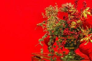 Close-up of Christmas tree branch decoration on table of living room. Garland, golden flowers, lights and rowanberries on spruce fir branches. Winter holidays composition with copy space photo