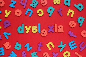 Color alphabet letters on red background. World Dyslexia Day concept. Solving the educational problem of reading. Medical and mental health awareness. Logopedy, psychology, learning lessons photo
