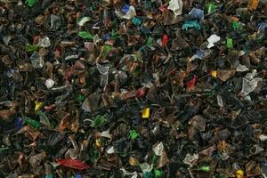 Shredded plastic pieces prepare for recycling. Raw cables material for reproduction. Sorting garbage on waste plant. Pile of scrap bottles on trash storage factory. Environmental concept photo