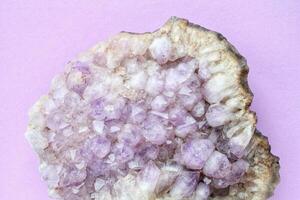 Violet amethyst gemstone crystal mineral on purple background with copy space. Natural stone. Geological sample of druse. Healing pebble photo