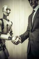 A robotic hand shakes the hand of a man in a grey suit, signifying a collaboration or agreement between the two. This image represents the integration of technology into photo