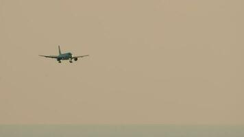 chorro avión que se acerca aterrizaje a puesta de sol. cinematográfico imágenes de un comercial aeronave moscas en contra el antecedentes de iluminado nubes video