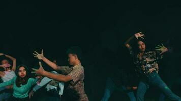 un grupo de asiático adolescentes jugando y bailando juntos en el oscuro de noche video