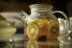 Fruit tea in teapot. Kettle on table. Fruits in summer. Healthy drink. photo