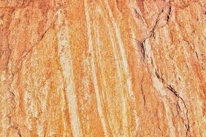Rock texture. Stone grunge background. Light brown rough backdrop. Red ginger pattern. Fragment of a mountain close-up. Rusty surface formation of a wall with cracks and layers. Copy space for text photo