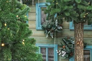 Christmas porch decoration idea. House entrance and window sill decorated for holidays. New year winter front yard festive snow tree garlands on facade photo