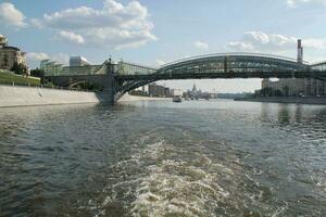 Andreevskiy Andreevsky bridge across the Moscow River at summer day. Arch of Pushkinskiy Pushkinsky pedestrian bridge. Moscow, Russia - June 22, 2023 photo