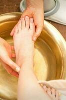 Washing female foot in a special container by male masseur in spa salon. photo