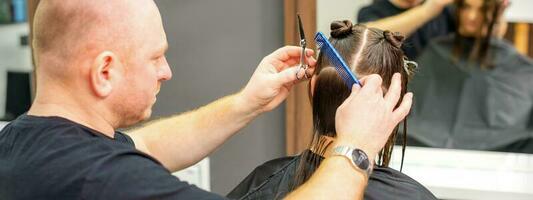 masculino estilista corte el pelo de hembra cliente en profesional belleza salón. foto