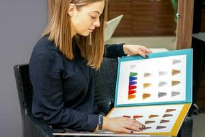 Young caucasian woman choosing a color from the hair color chart in a beauty salon. photo