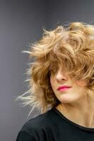 Portrait of beautiful young white woman with a curly light brown medium length hairstyle on dark background. photo