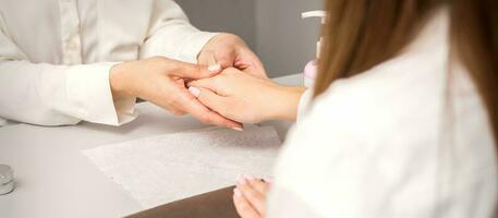 Manicure master massaging female hands before nail procedure in a nail salon. photo