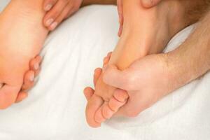 Relaxing double massage on the female feet by two masseurs in spa salon. photo