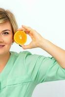 Portrait of young smiling blonde woman cosmetologist with halves of oranges on white background. photo