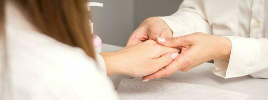 Manicure master massaging female hands before nail procedure in a nail salon. photo