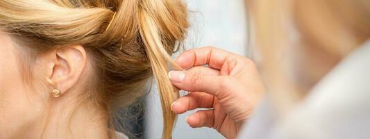 de cerca peluquero peinado rubia pelo en el espalda de el cabeza en un belleza salón. foto