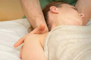 Young caucasian woman having a massage on the shoulder in spa salon. photo