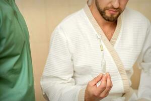 Young caucasian man receiving nasal inhalation Maholda with essential oil in the nose at a hospital. photo