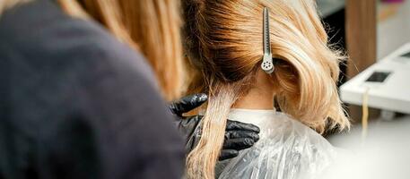 A hairdresser is applying color to the hair of a customer. Hair coloring in a beauty salon. Beauty and people concept. Close-up back view. photo