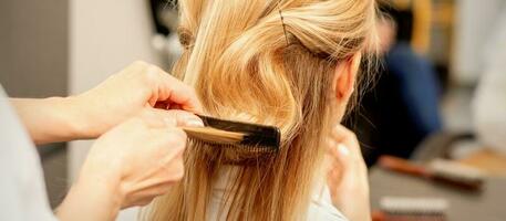 A hairdresser is combing female hairstyling in a hairdressing beauty salon. photo