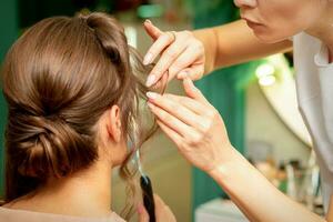 cerca arriba peluquero estilista hace peinado para un joven mujer en un belleza salón. foto