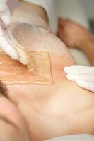 Young caucasian man receiving hair removal from his chest in a beauty salon, depilation men's torso. photo