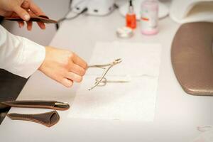 Nail nippers in the hand of female manicure master putting to the towel before nail care in manicure salon. photo