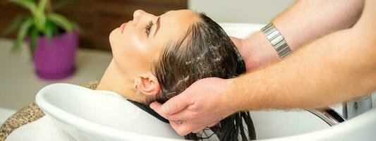 Beautiful caucasian woman washing hair in a beauty salon. photo