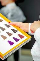 Young caucasian woman choosing a color from the hair color chart in a beauty salon. photo