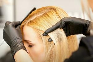 un peluquero es peinada hembra cortes de cabello en un peluquería belleza salón. foto