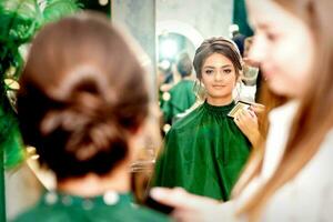 Make-up artist doing makeup for young beautiful bride applying wedding makeup in a beauty salon. photo