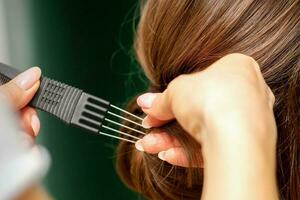 Close Up hairdresser stylist makes hairstyle for a young woman in a beauty salon. photo