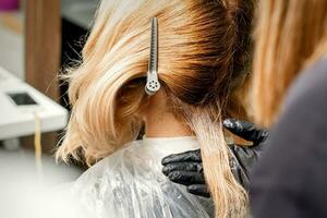 A hairdresser is applying color to the hair of a customer. Hair coloring in a beauty salon. Beauty and people concept. Close-up back view. photo