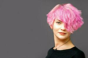 Portrait of beautiful young white woman with a pink short hairstyle on dark background with copy space. photo