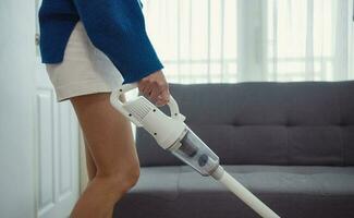 Close-up of young woman using a vacuum cleaner at home. photo