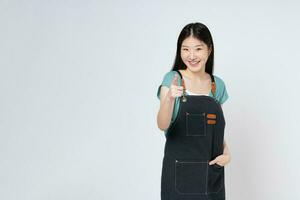 Young woman chef or waiter smiling and pointing forward, looking at camera isolated on white background. photo