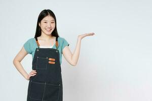 Young woman wearing kitchen apron, presenting or showing open hand palm with copy space for product isolated on white background. photo