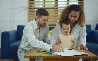 Dad, Mom and little daughter drawing with colorful pencils on paper happy smiling.Young family spend free time together in living room at home. photo