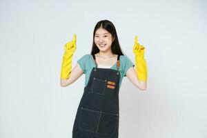 Portrait of young woman wearing yellow rubber gloves for hands protection and pointing to empty copy space isolated on white background. photo