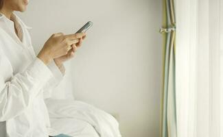 Relaxed woman using smart phone in the morning in bed at home. photo