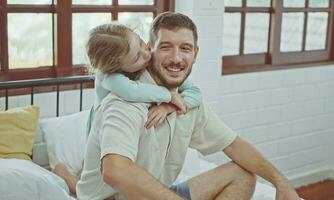 pequeño niña besos su papá en mejilla, contento padre. foto