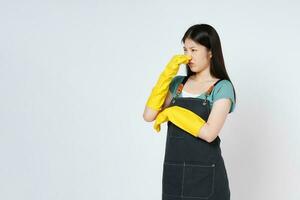 Portrait of young woman wearing yellow rubber gloves covered her nose with her hand an unpleasant smell isolated on white background. photo