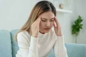 Headache, female having migraine pain, bad health, Asian woman feeling stress and headache, Office syndrome, sad tired touching forehead having migraine or depression, irritated girl, sadness grief photo