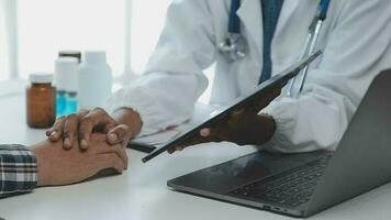 Medical worker in lab coat and sterile mask, doing a microscope analysis while her colleague are working behind video