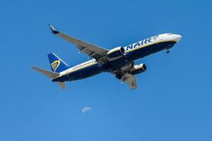 Irish air company Ryanair with aircraft Boeing 737-8AS approaching to land at Lisbon International Airport against blue sky photo