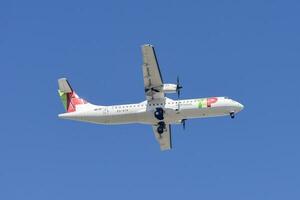 Portuguese company Tap with aircraft ATR 72-600 approaching to land at Lisbon International Airport against blue sky photo