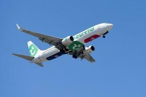 Dutch based Transavia air company with aircraft Boeing 737-8GJ approaching to land at Lisbon International Airport against blue sky photo